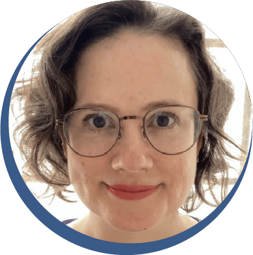 Headshot of a smiling woman with short curly brown hair and glasses, wearing a purple top.
