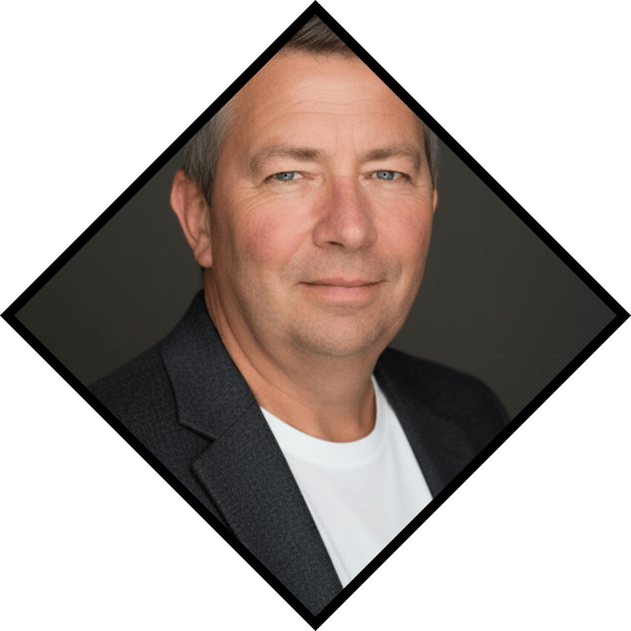 Smiling middle-aged man with grey hair and blue eyes, wearing a dark jacket over a white t-shirt.