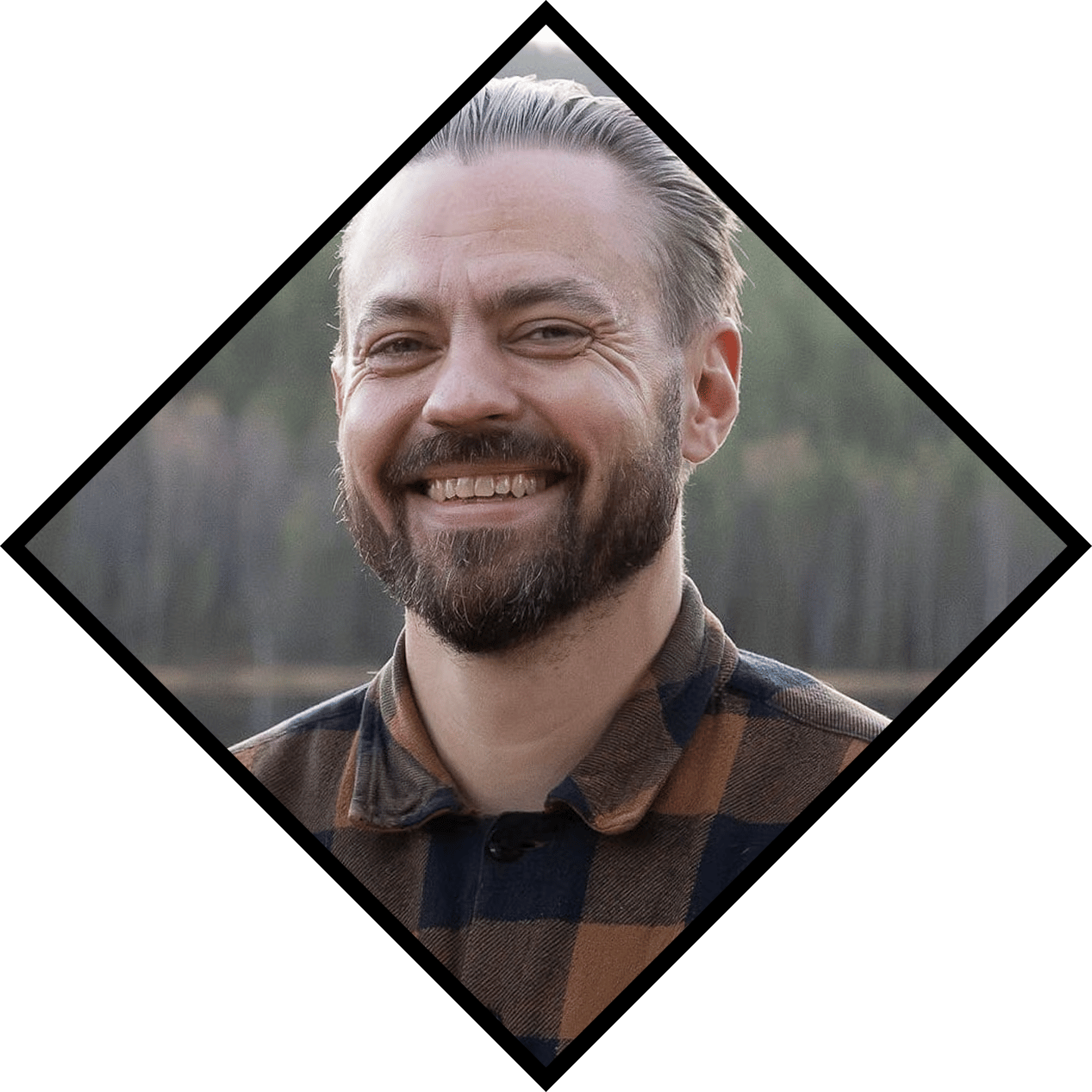 Smiling man with a beard and plaid shirt, framed in a black diamond shape.