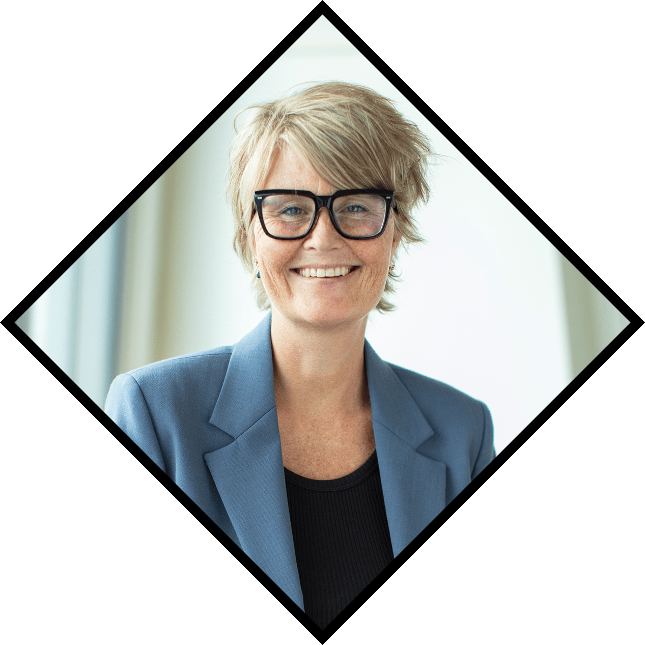 Smiling woman with short blonde hair, black glasses, and a blue blazer.