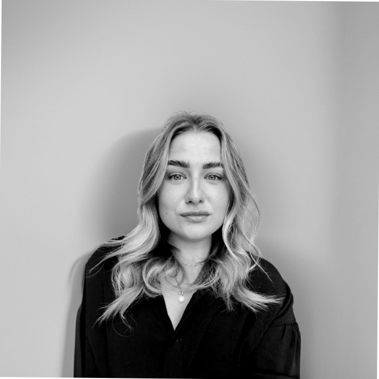 Monochrome portrait of a young woman with long wavy blonde hair, looking forward.