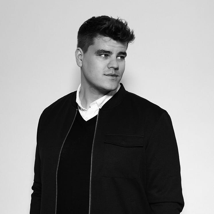 Black and white portrait of a man in a black jacket and white shirt, looking left.