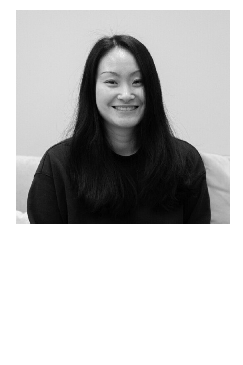 Black and white portrait of a smiling East Asian woman with long dark hair and a dark sweater.