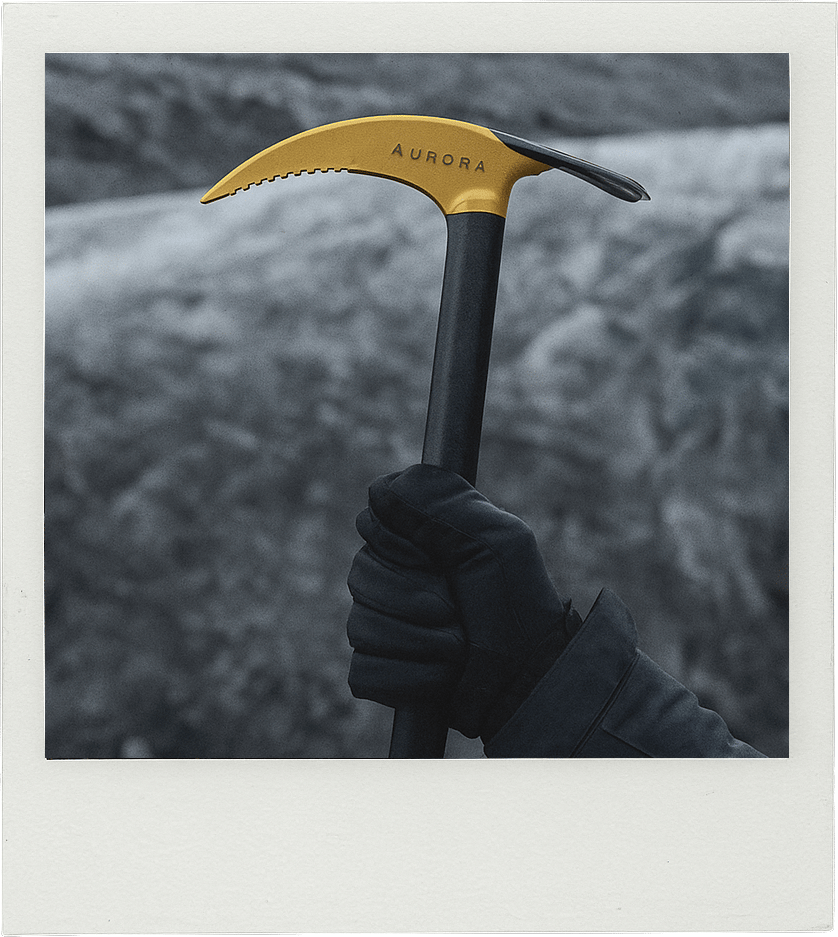 Gloved hand holding a yellow Aurora ice axe against a desaturated background.
