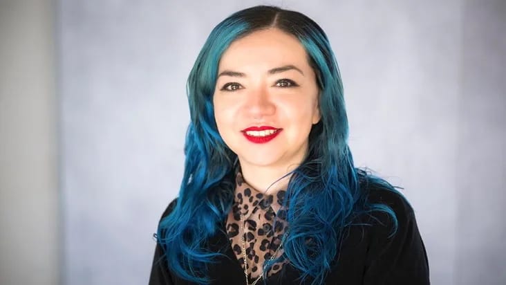 Smiling woman with bright blue hair and red lipstick.