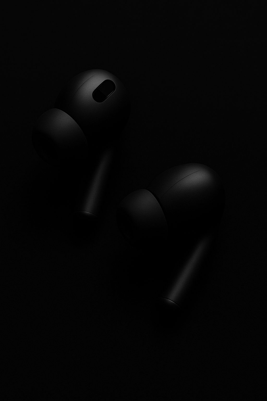 Two dark wireless earbuds are subtly lit against a black background.