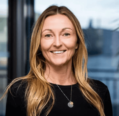 Smiling woman with long blonde hair wearing a black top.