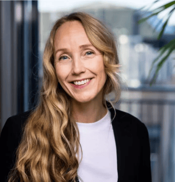Smiling blonde woman in a white shirt and black jacket.