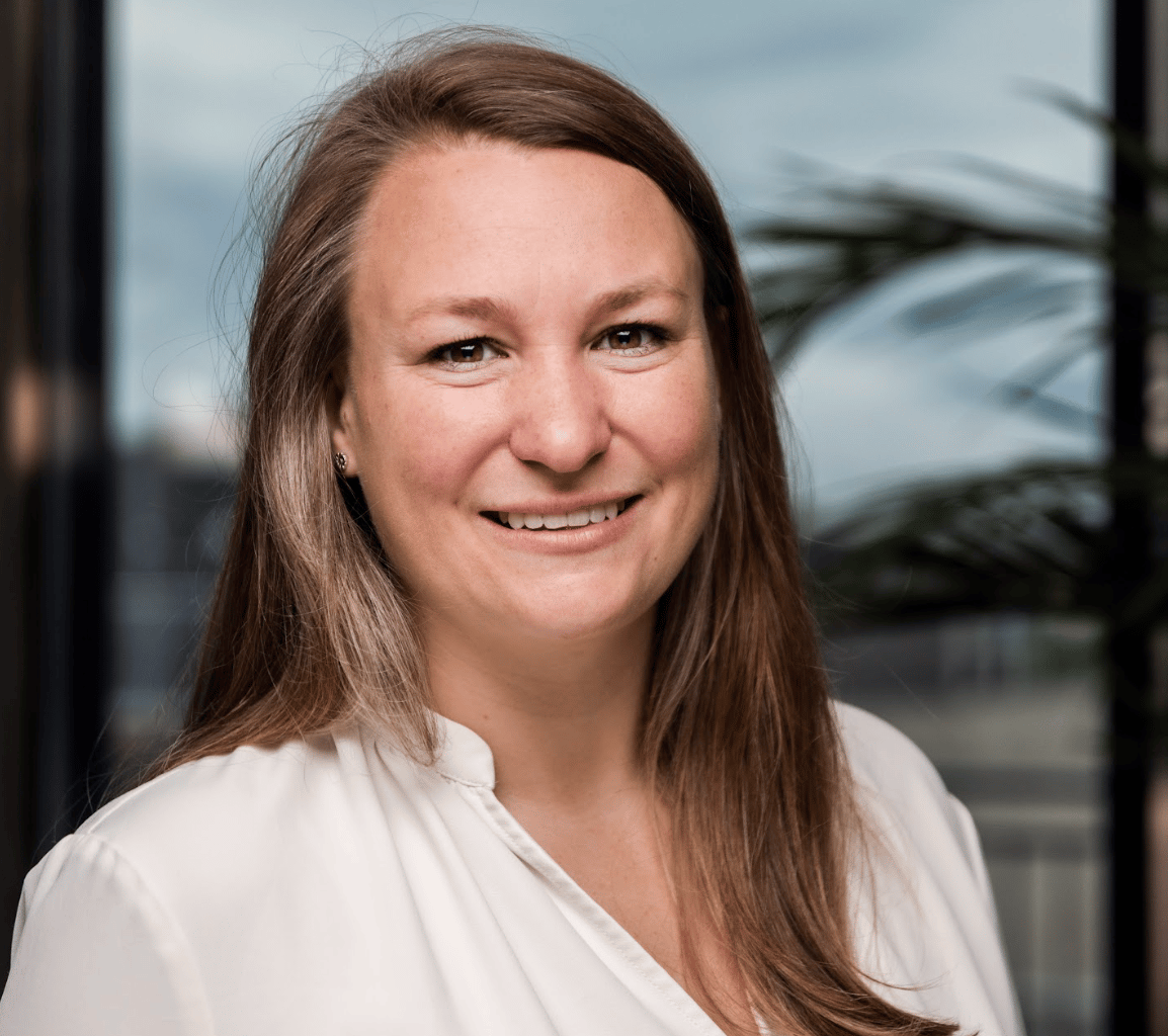 Smiling woman in a white shirt with long brown hair.