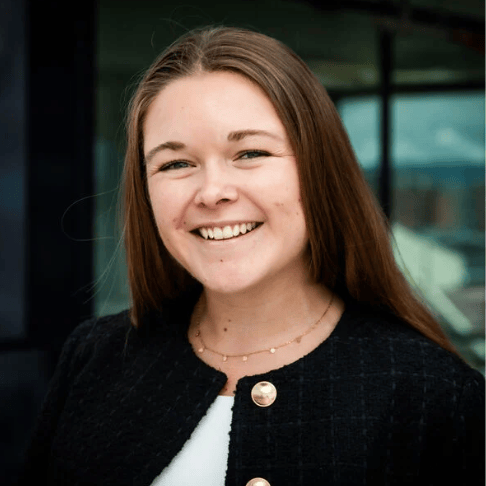 Smiling woman with long brown hair in a black jacket.