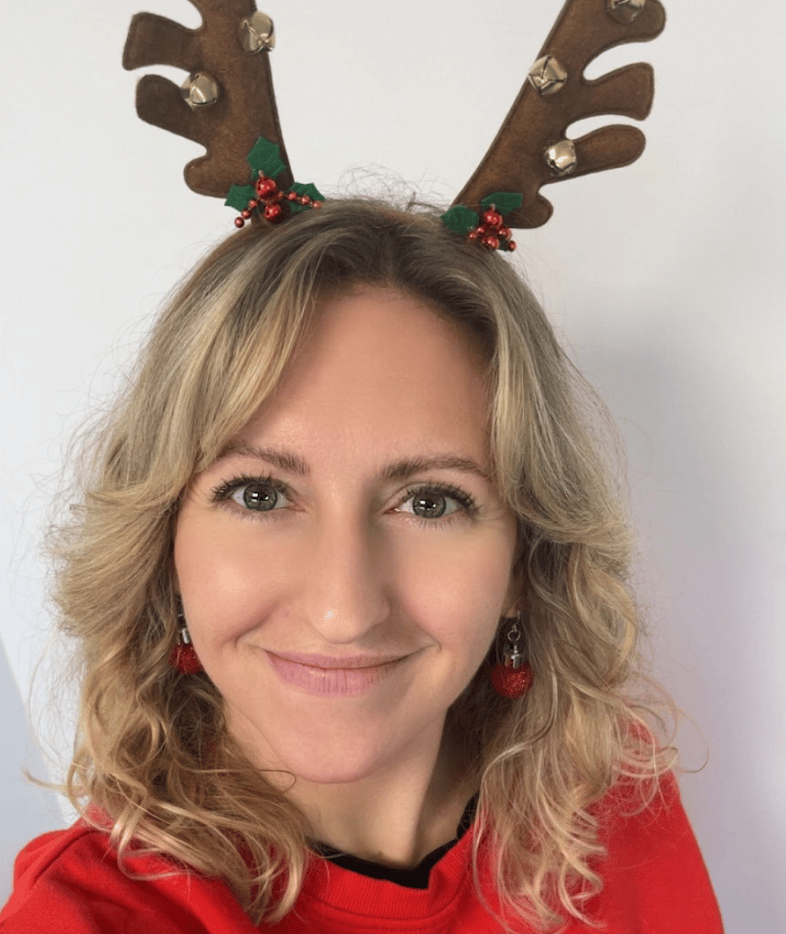 Smiling woman in reindeer antlers and red top.