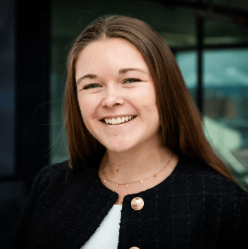 Smiling woman with long brown hair, wearing a black jacket.