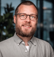 Headshot of a smiling man with glasses and a beard.