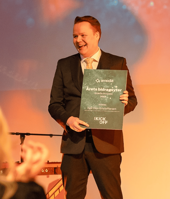 Egil Olav Kristoffersen smiles, holding Amedia's "Årets bidragsyter" award.
