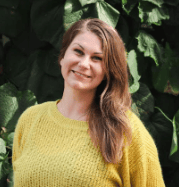 Smiling woman in yellow sweater with green background.