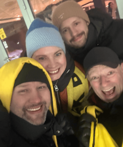 Four happy people in winter clothes and hats smiling for a selfie.