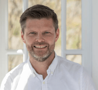 Smiling man with beard in white shirt.