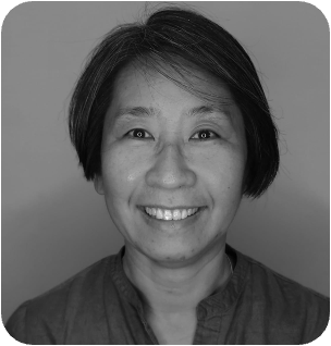 Black and white headshot of a smiling Asian woman with short, dark hair, looking at the camera.