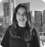 Black and white portrait of a smiling young woman with long hair and a city skyline background.