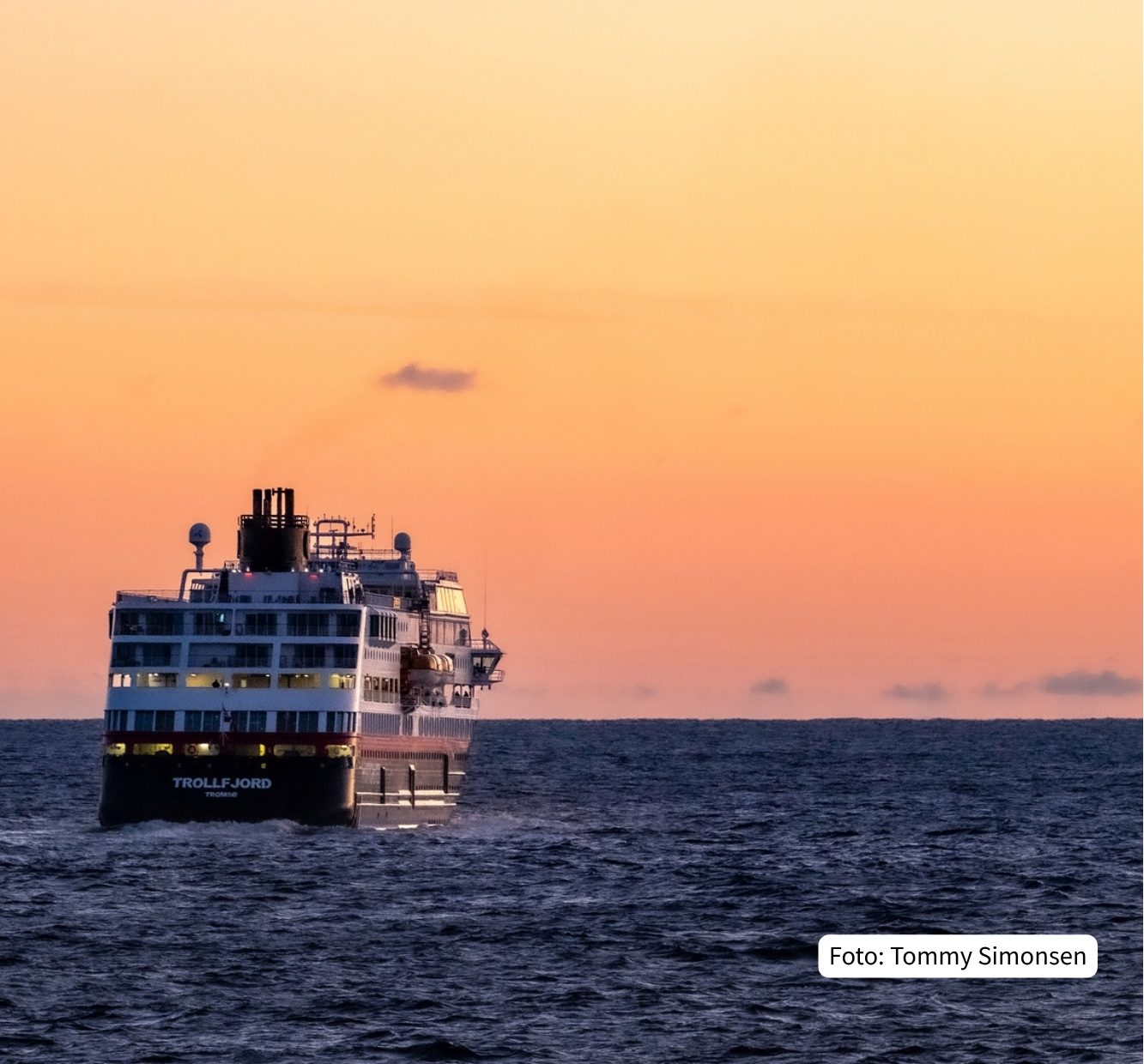 Cruise ship TROLLFJORD sailing on the ocean at sunset with an orange sky.