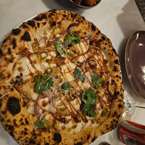 A close-up of a delicious BBQ chicken pizza with cheese, red onion, and fresh cilantro.