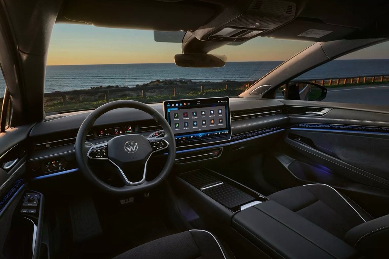 Volkswagen car interior with dashboard, steering wheel, and ocean view at sunset.