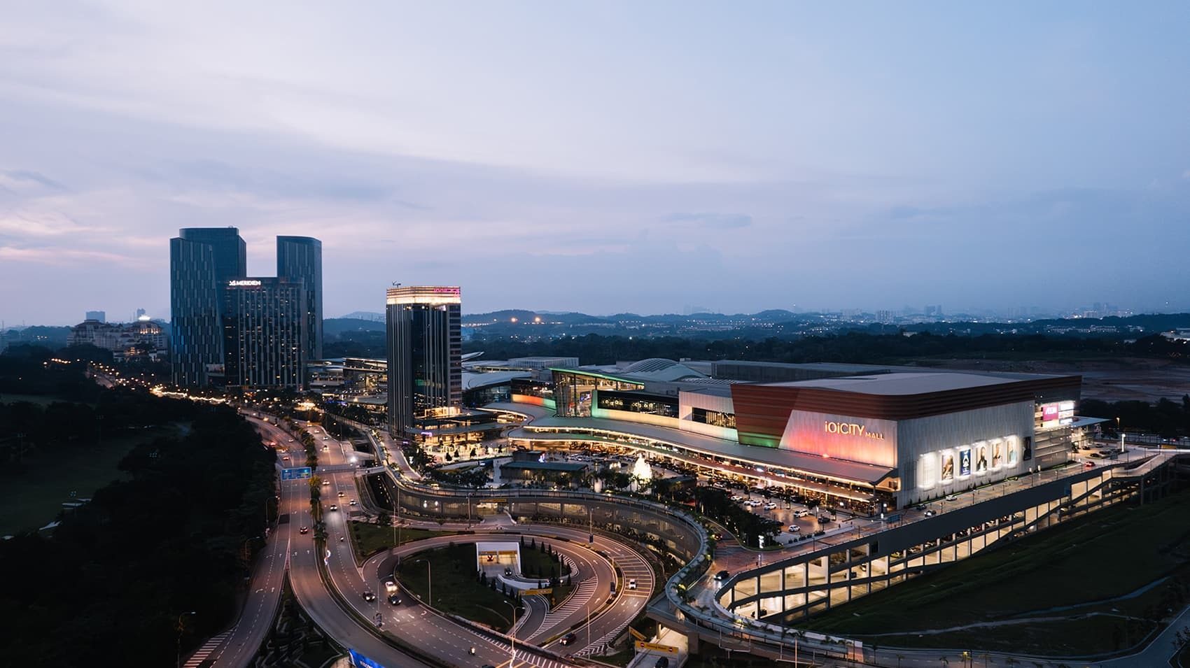 Dusk aerial view of IOI City Mall, Le Meridien hotel, and a modern city complex with busy roads.
