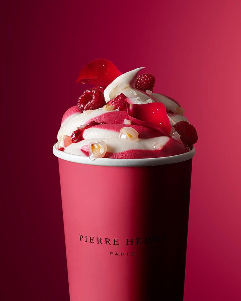 A pink Pierre Herme cup with swirled raspberry ice cream, topped with raspberries, rose petals, and lychee.