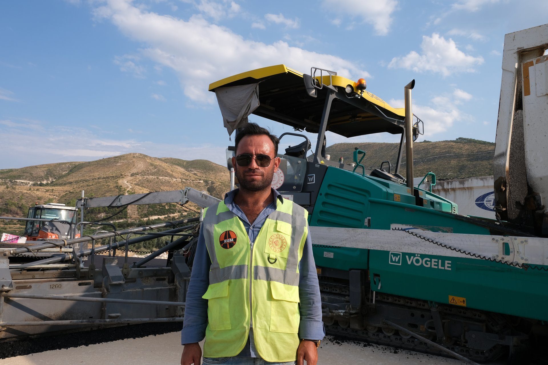 Motor vehicle, Automotive tire, Sky, Cloud, Mountain, Workwear, Asphalt, Yellow, Travel