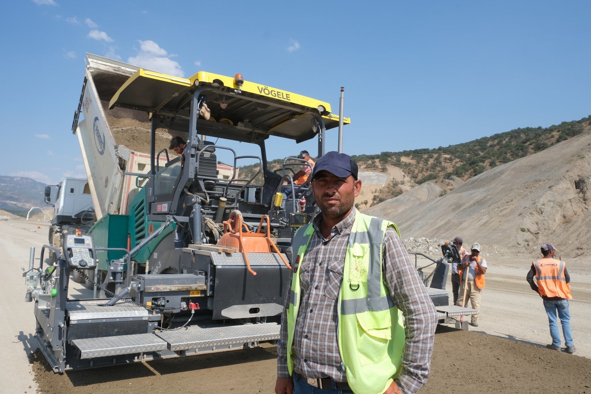 Automotive tire, Road surface, High-visibility clothing, Hard hat, Sky, Vehicle, Wheel, Asphalt, Cloud