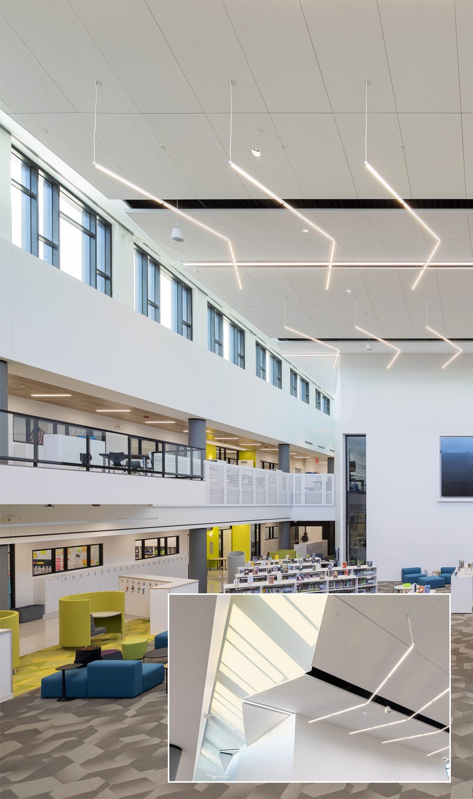 Mostly white designed media center interior with white ceiling system and hanging angular lighting.