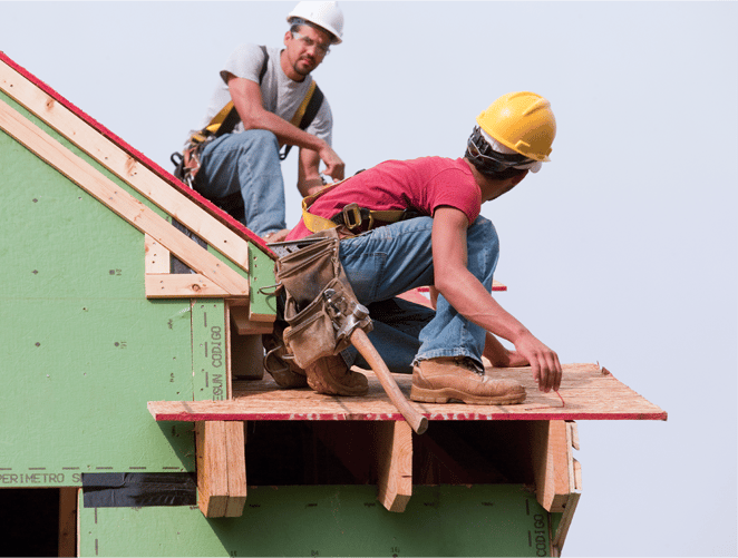 two roofers in hardhats building a roof