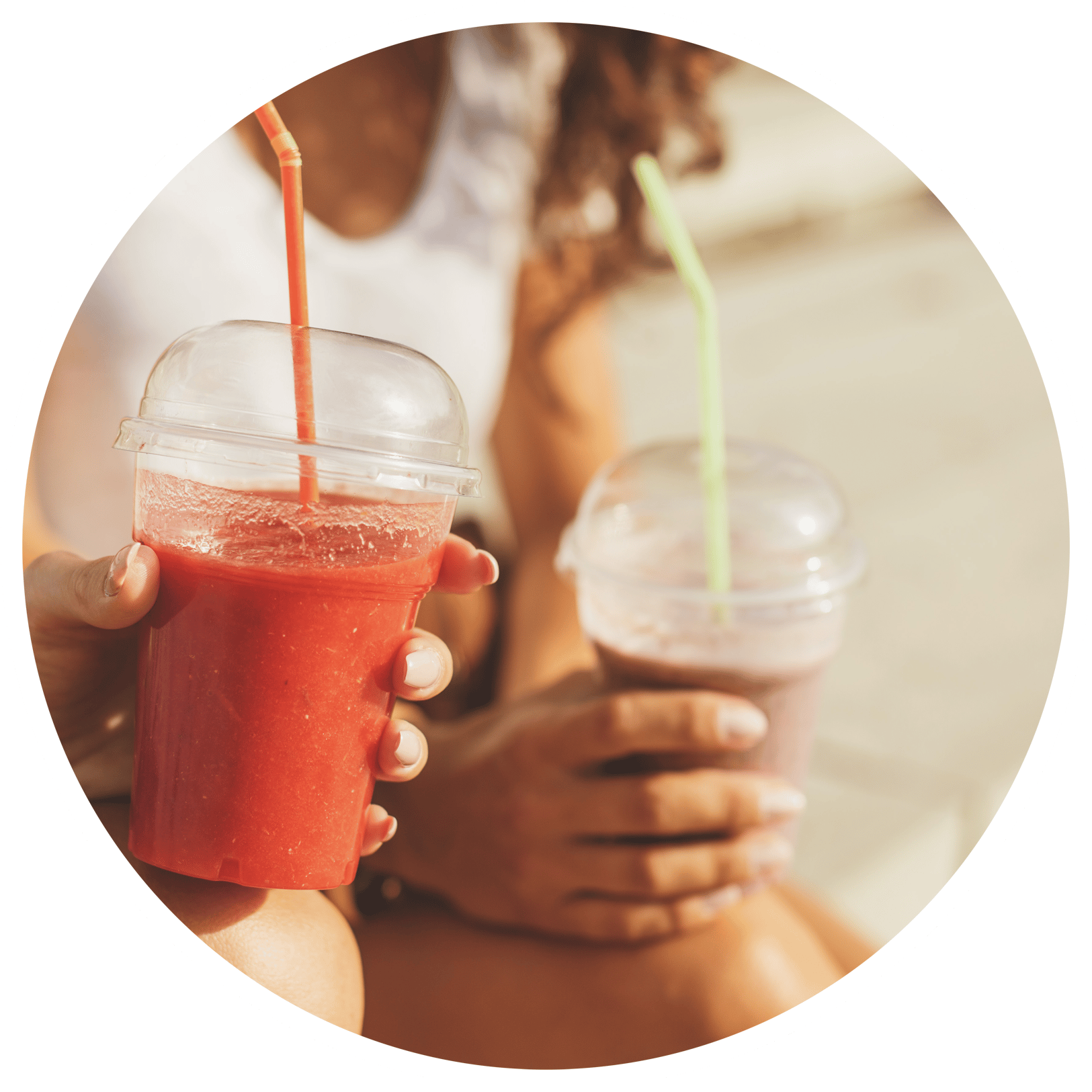 closeup of two hands holding colorful smoothies with straws