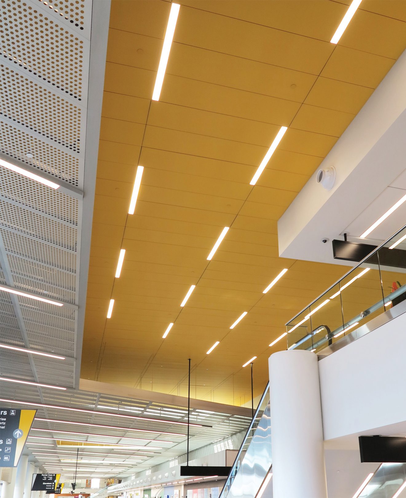 View looking upward at bright yellow airport ceiling system with built in lighting.