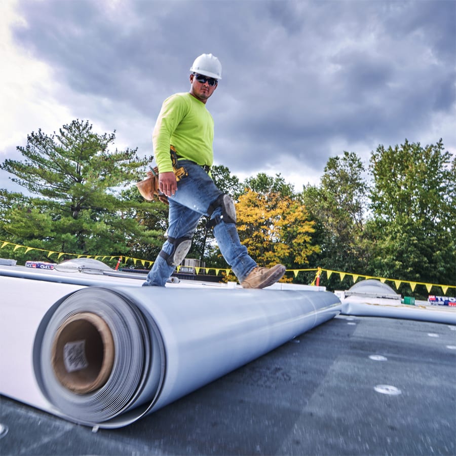 roofer with his foot on a roll of single-ply material