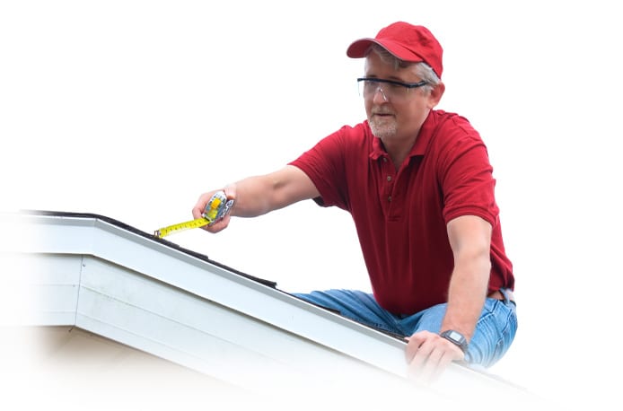 Man in red shirt and baseball cap measuring a roofline
