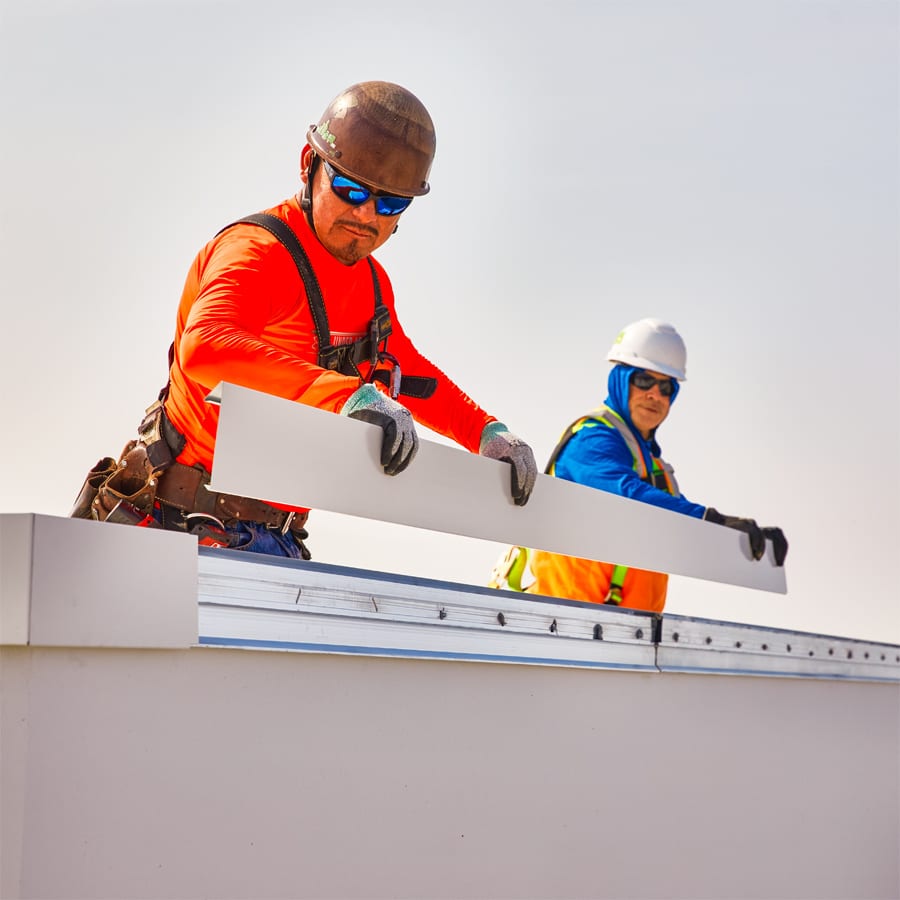 two skilled roofers installing a portion of edge metal