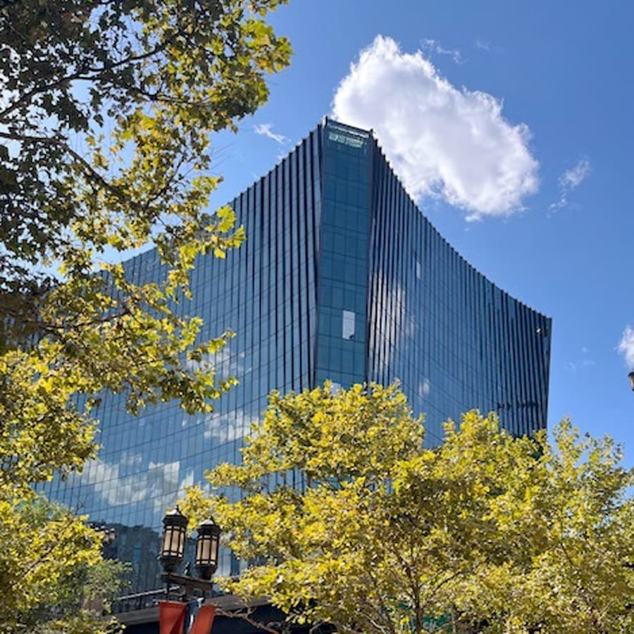 10 World Trade view from a distance through trees under a blue sky with billowy cloud.