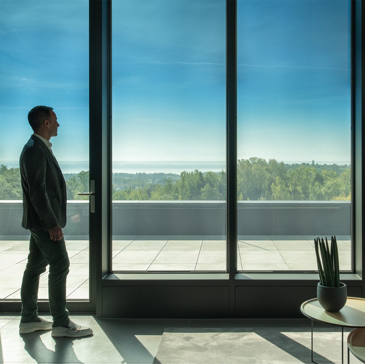 Interior shot of a business man looking through tinted office windows at the expansive view