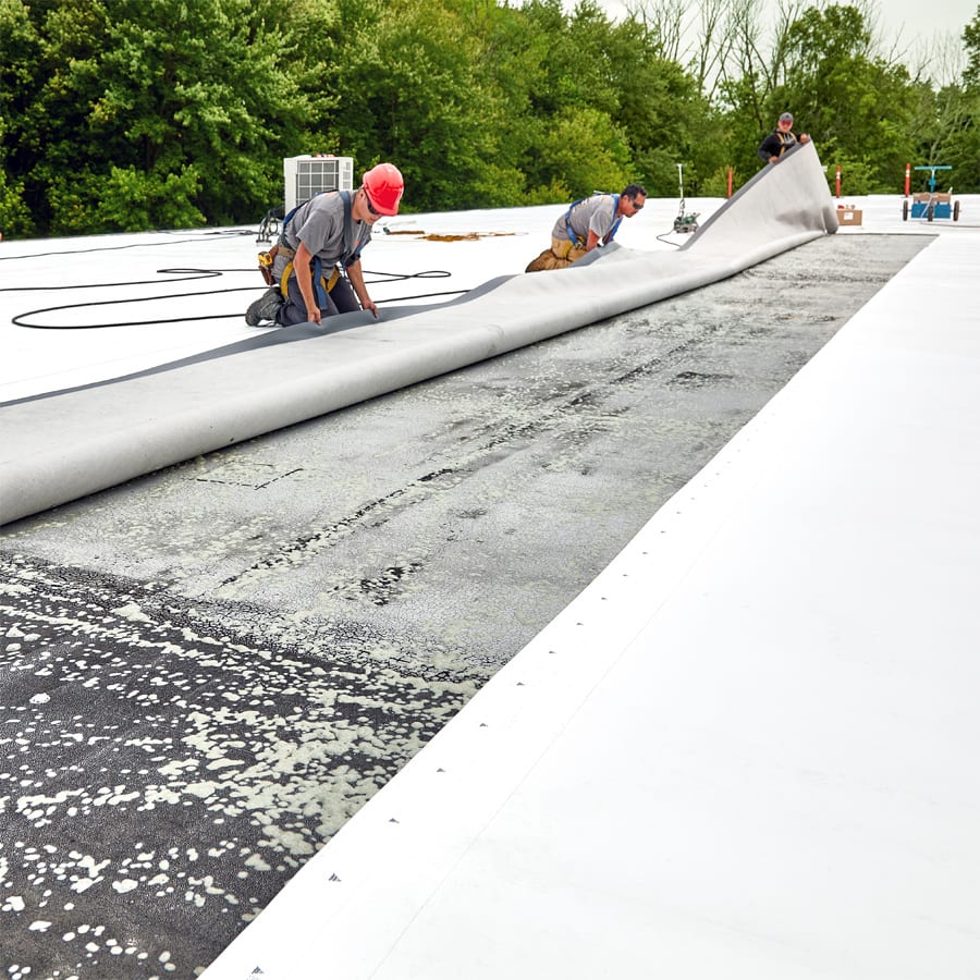 Roofers applying adhesive to a commercial roof