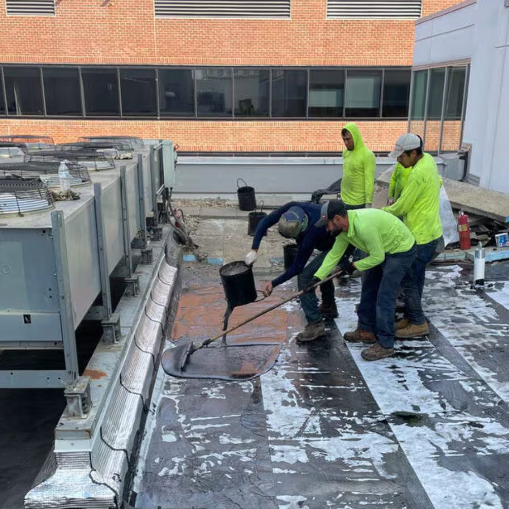 Roof crew applying hot rubberized asphalt.