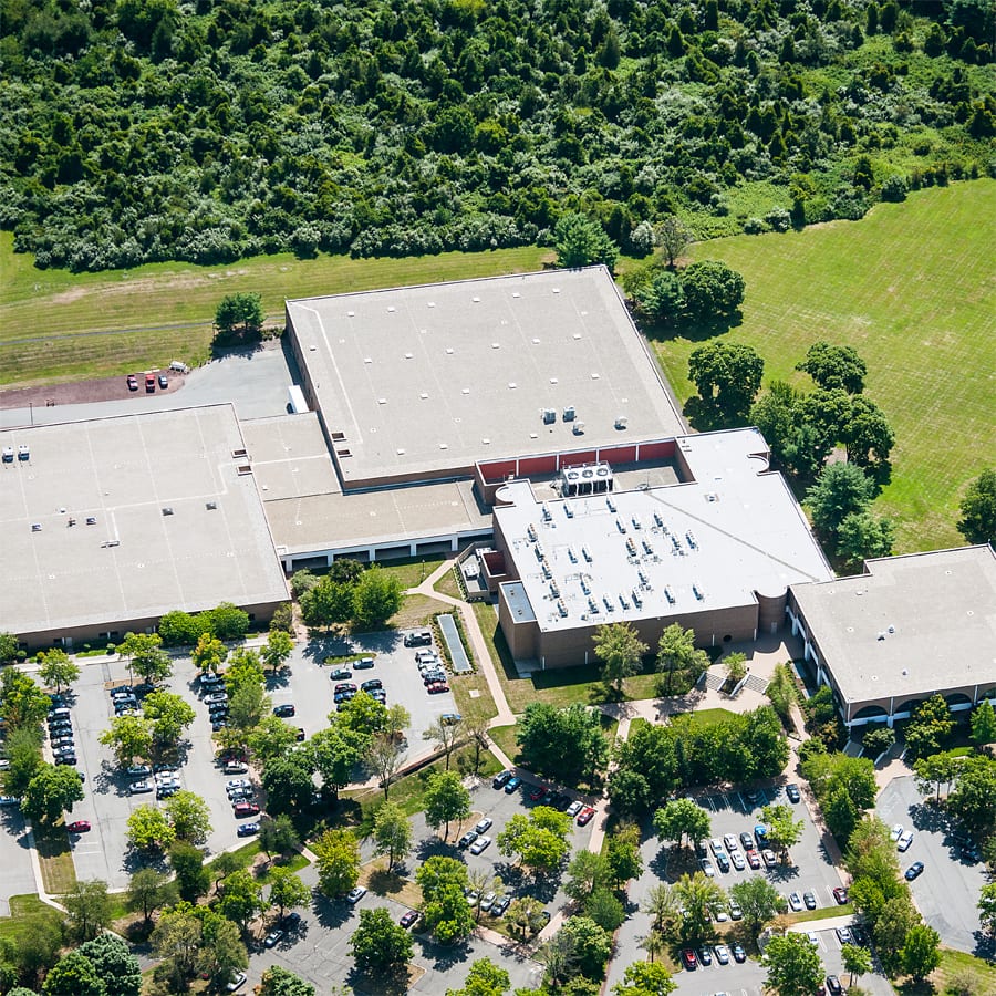 Aerial view of a large building complex with parking lots, surrounded by trees and forest.