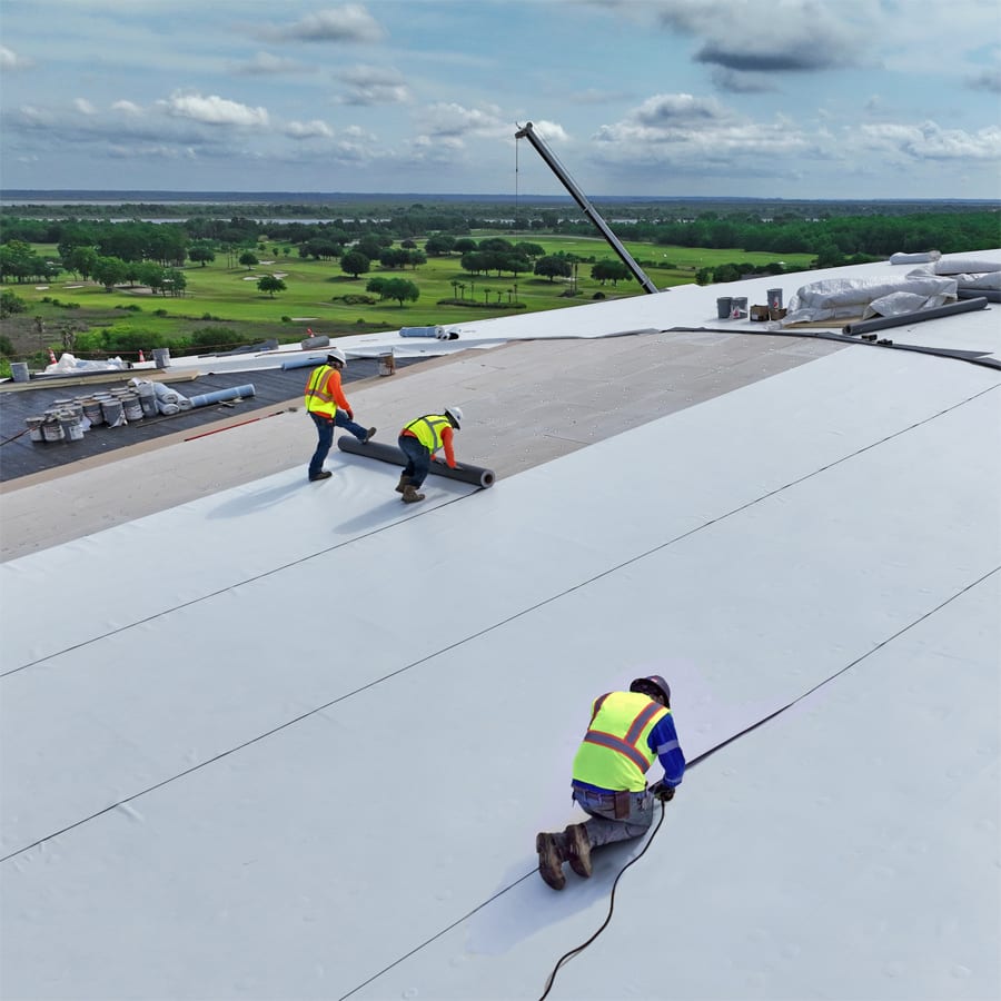 roofers installing pvc membrane high up on a convention center