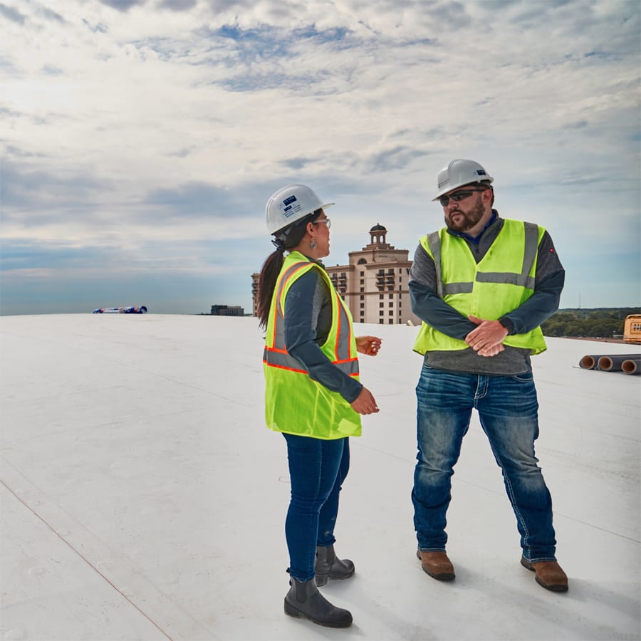Two engineers in safety gear having a conversation atop the Savannah Convention Center during a roof install.