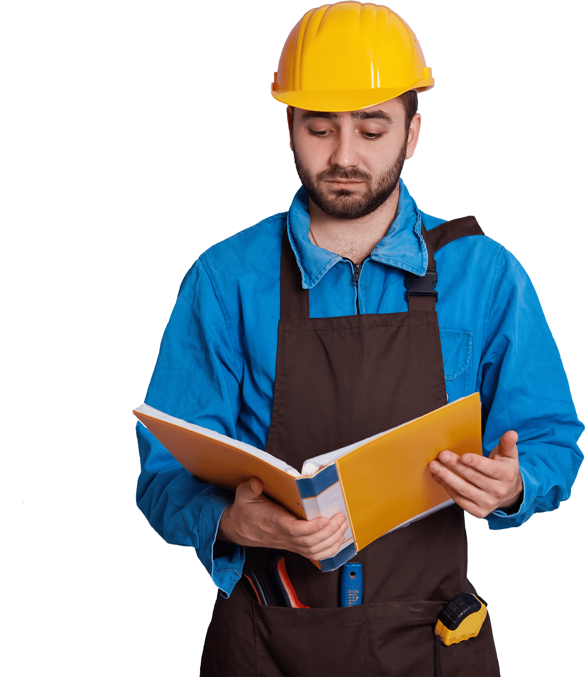 Man in yellow hard hat and work apron full of tools reading a book seriously.