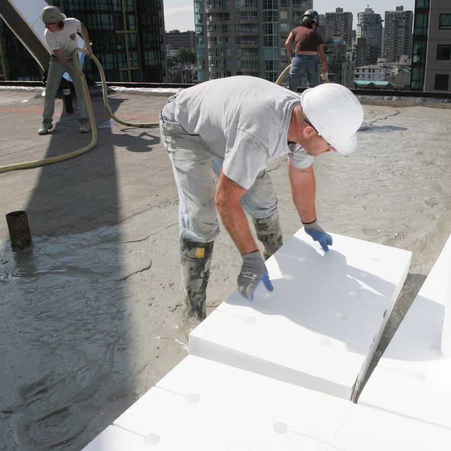 Roofer standing in wet concrete, installing roof acoustic panels