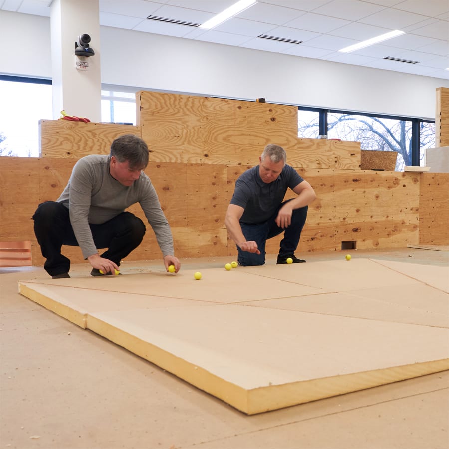 two men crouched over tapered insulation