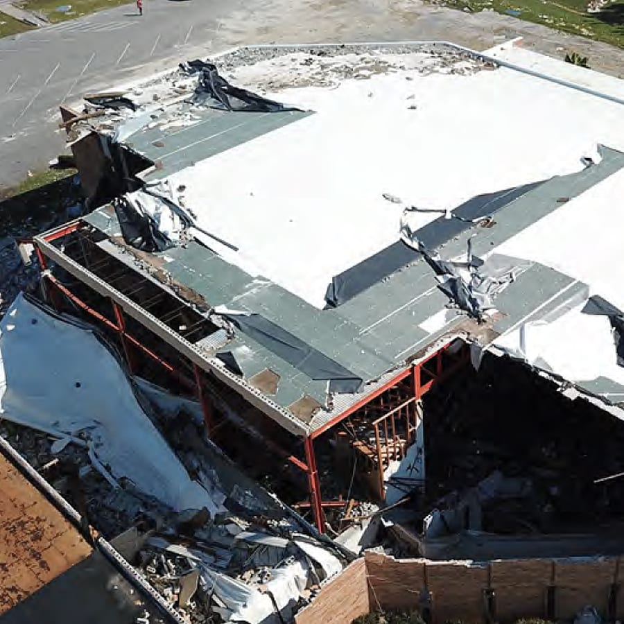 Aerial view of a commercial roof with major weather damage.