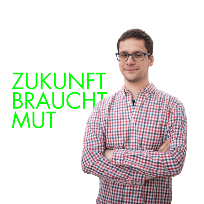 Smiling man with glasses, plaid shirt, arms crossed. Green text: ZUKUNFT BRAUCHT MUT.