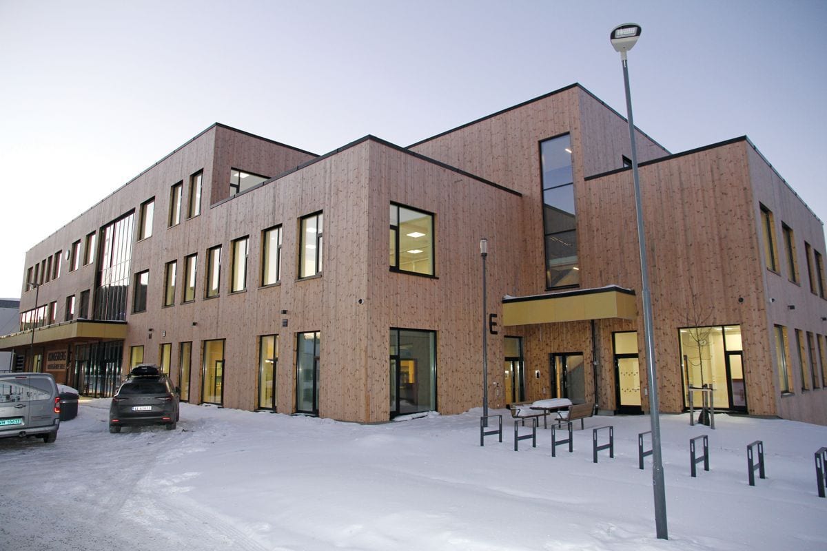 Modern wood-clad building in snow, with cars and streetlights.